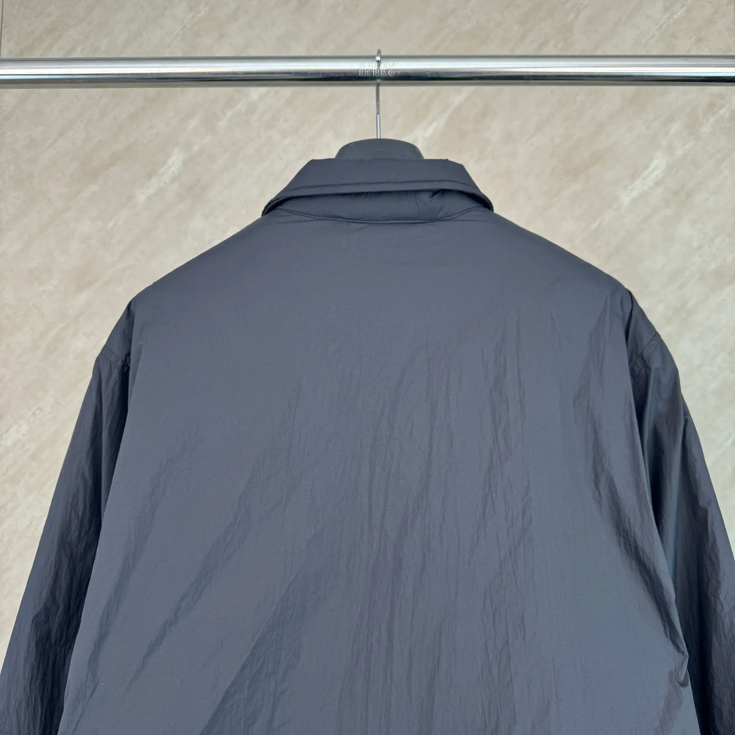 P670 25FW Ralph Lauren red label light cotton jacket (coach jacket) size s m l xl Fabric procurement: a combination of pragmatism and classic texture Material: high-density nylon taffeta Features: density is about 210T-300T, smooth and slightly matte surface, excellent windproof and waterproof performance (with DWR water-repellent treatment), strong wrinkle resistance and easy care, in line with the positioning of American casual "durable and practical".  Color: Classic dark black, using vat dyeing process (dye penetrates into the fiber), the color fastness reaches ISO level 4 or above to avoid fading or color transfer after washing.  2. Lining fabric Material: Lightweight cotton-polyester blended lining (65% Polyester + 35% Cotton) Function: Reduce friction between the fabric and inner clothing, improve wearing smoothness; blended material has both breathability and durability to avoid the stuffy feeling of pure nylon lining.  Version and cutting process Version: Classic Coach Jacket, loose version, slightly dropped shoulder line (shoulder width is 1-2cm wider than the standard version), length to the hips, and slightly tapered straight sleeves, taking into account both freedom of movement and casual style.  Embroidery technology: Polo horse logo on the left chest: flat satin stitch embroidery (satin embroidery), embroidery thread: 100% polyester high color fastness embroidery thread (the color number is consistent with the brand’s standard red color card), stitch density 12-15 stitches/cm, the outline of the horse logo is clear, and the details of the rider and horse are burr-free.  Embroidery positioning: precise positioning through the template (12cm from the neckline and 8cm from the placket) to ensure left and right symmetry and centering.  Topstitching technology: The seams of the body are made of double-needle flat seams (needle pitch 3cm/10 needles), the stitches are smooth and straight, the stitching color is dark black (the same color as the fabric), and the stitch width is 0.5cm, which enhances firmness while forming simple decorative lines.  1. Main body splicing, splicing of the front placket and body: The placket is made of double-layer folding + flat seam splicing, with a thickness of about 0.3cm to ensure that the buttons are not easily deformed when fixed; the edges of the placket are cut with a hot knife to avoid burrs.  Sleeve panels are spliced ​​to the body: the armholes are spliced ​​with round-head keyhole machine seams + flat seams. After splicing, the armholes have a natural curvature and no sense of tightness during movement; the height of the sleeves is about 8-10cm, which is in line with the loose characteristics of casual jackets.  Main button: black urea resin button, matte surface treatment, buttonholes are hand-made keyholes (6 strands of cotton thread, keyhole density 8 stitches/mm), the edges of the eyelets are smooth and without burrs.  Collar buttons: The first button on the collar is a hidden button (diameter 12mm), which prevents the collar from opening and improves the neatness of wearing.